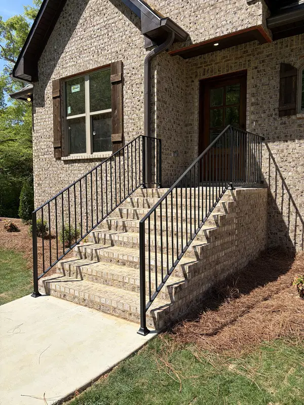Custom black metal railings installed along exterior masonry steps