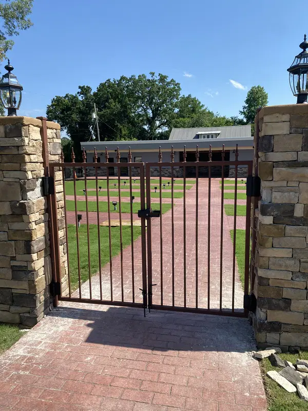 Custom ornamental iron gate installed between stone columns